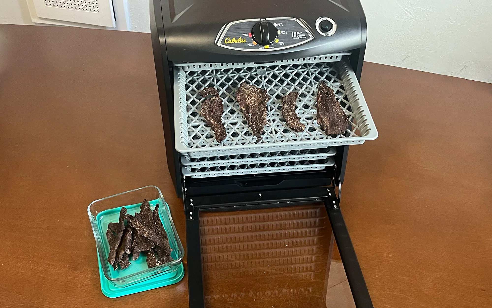Le déshydrateur Cabela's est posé sur une table avec de la viande séchée à l'intérieur.