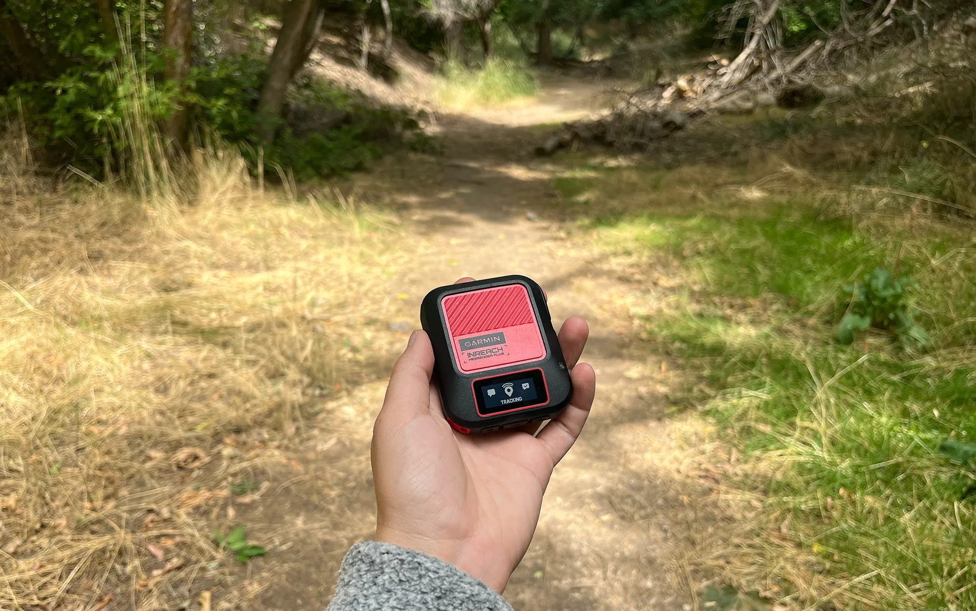 Un randonneur tient un appareil Messenger Plus sur le sentier.