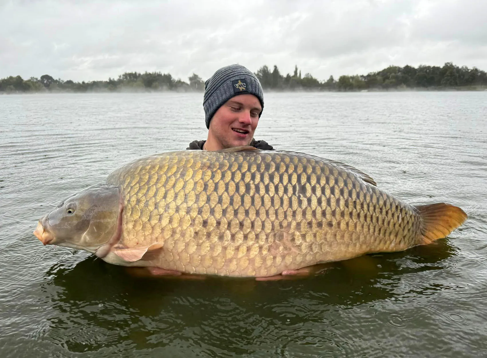 Un pêcheur polonais brandit une carpe commune de taille record du monde.
