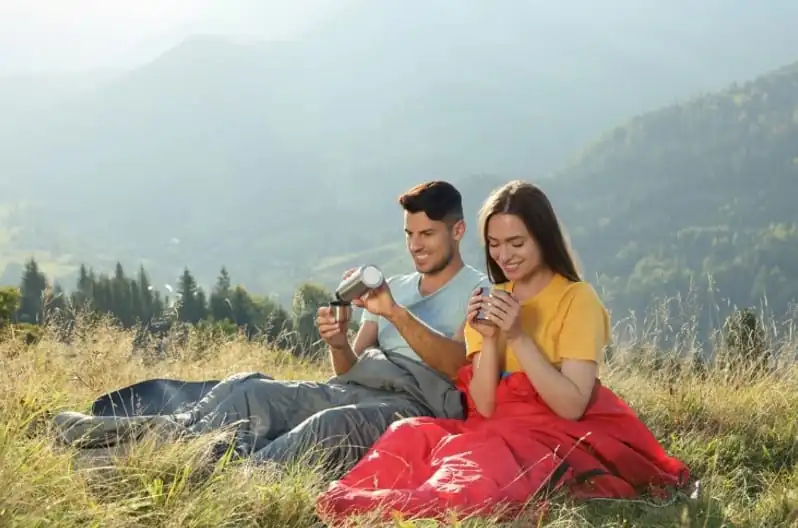 couple dans un sac de bivouac prenant un verre