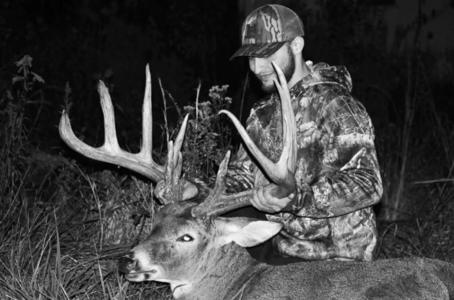 Une photo en noir et blanc de CJ Alexander avec le Giant Ohio Buck qu'il a braconné en 2023.