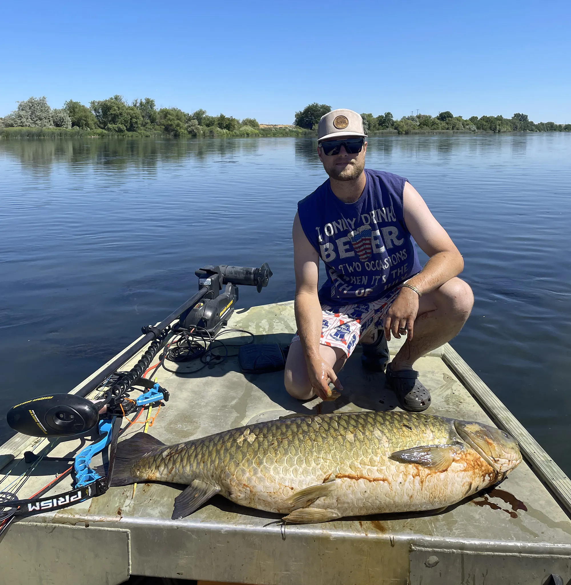 Un Bowfisherman de l'Idaho avec une carpe d'herbe géante tirée de son bateau.
