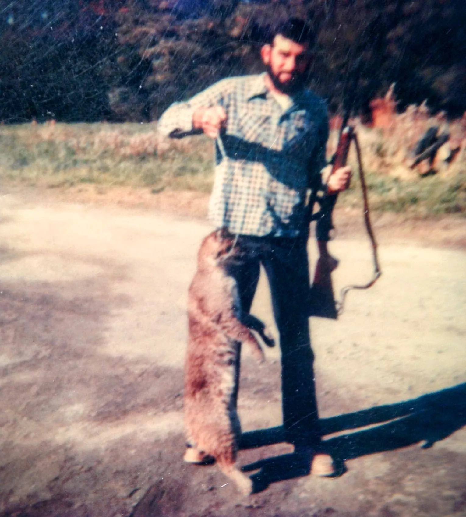 Une vieille photo instantanée d'un homme tenant un fusil et un lynx roux
