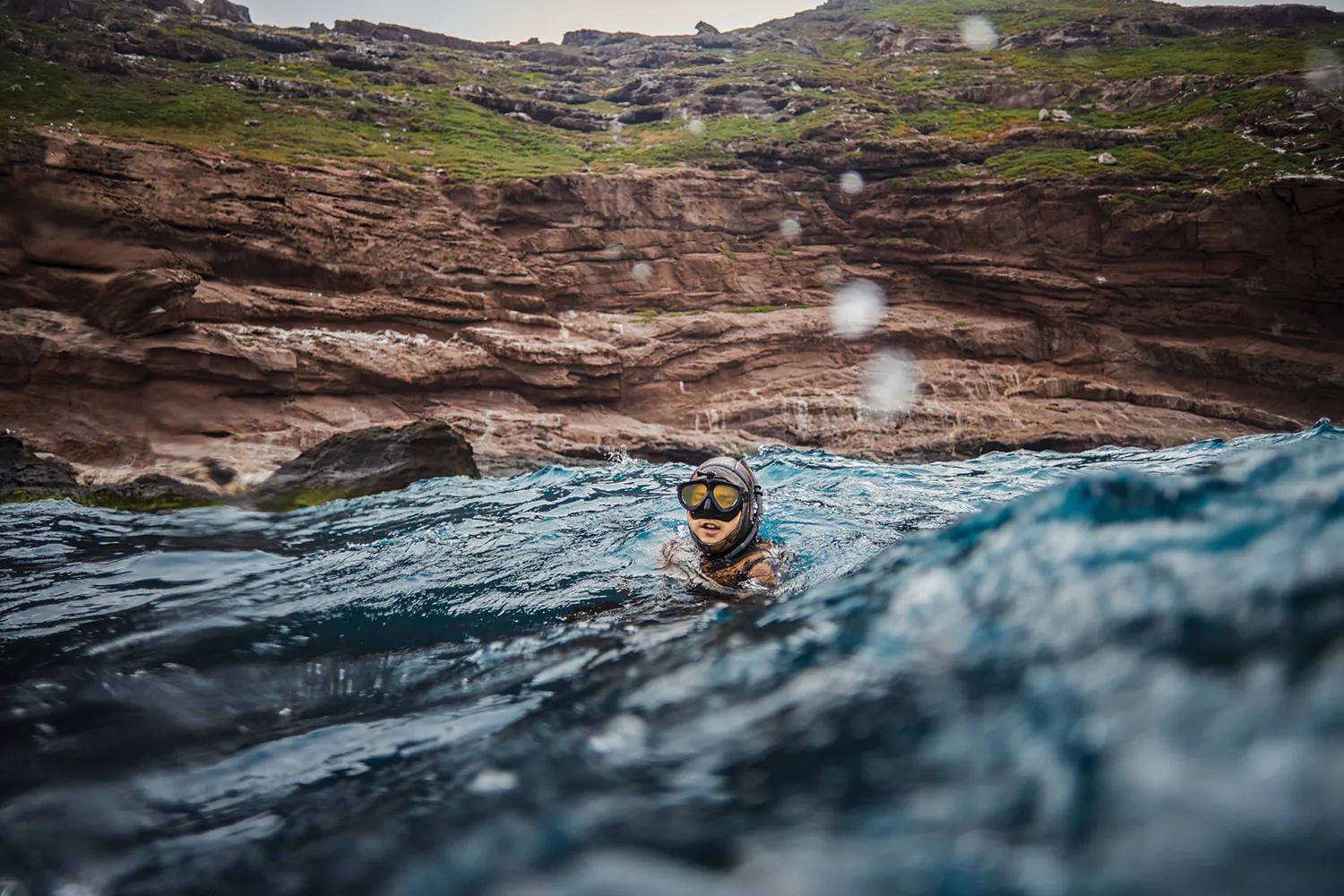 Spearfisherman avec la tête au-dessus de l'eau dans une zone rocheuse et agitée