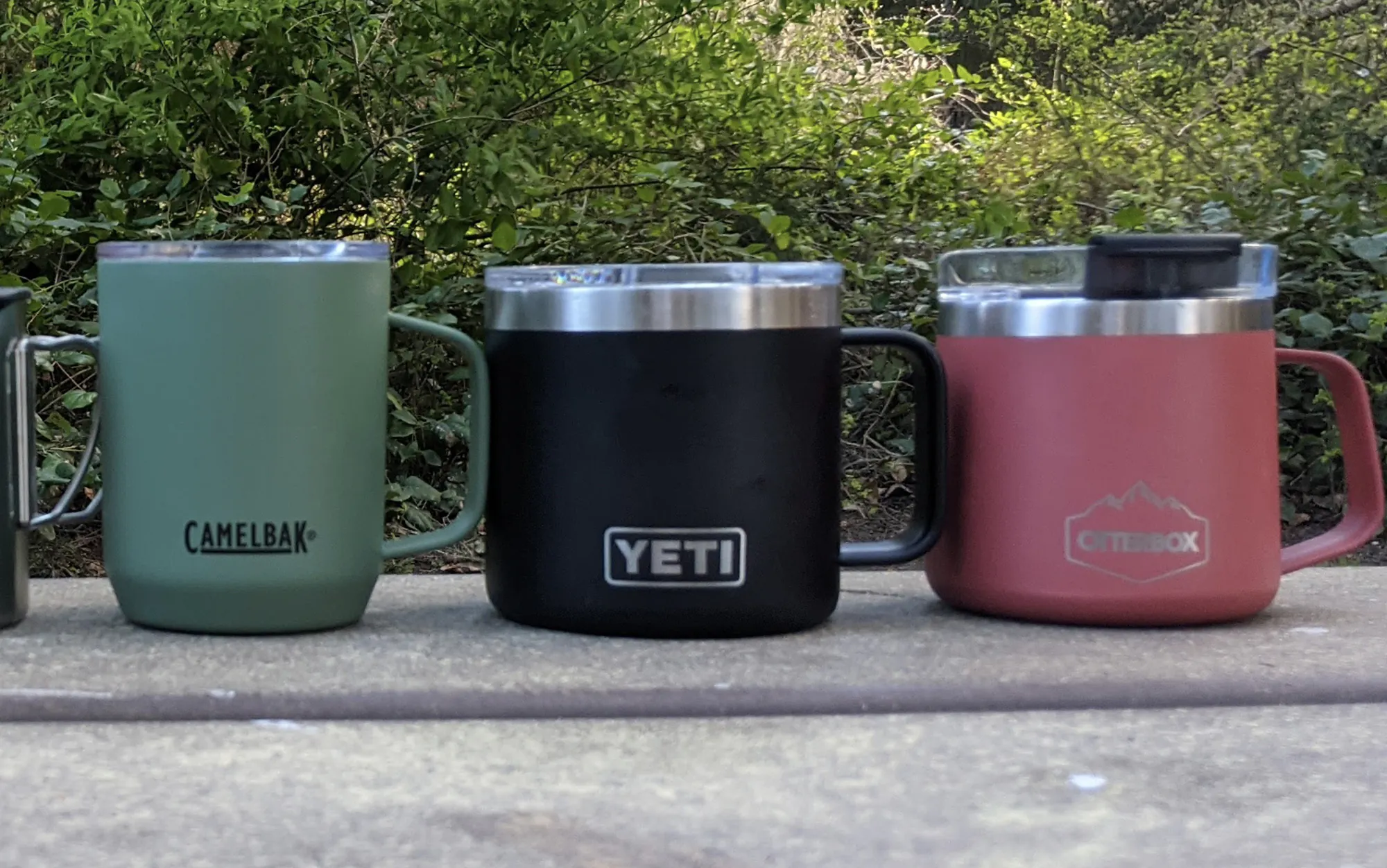 Trois tasses de camping assises sur une table avec le Yeti au milieu