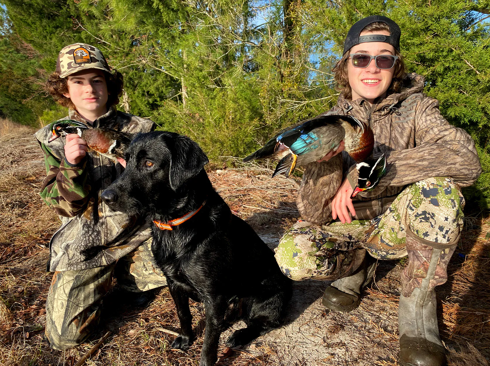 Deux chasseurs de canards et un laboratoire avec une paire de canards en bois.