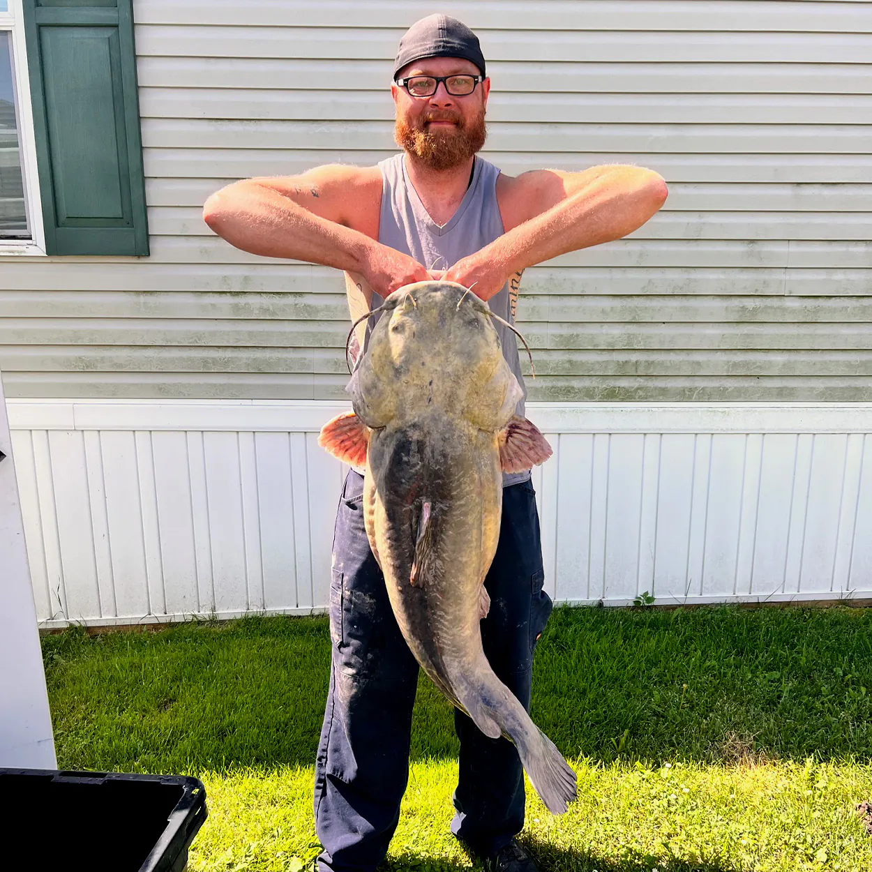 Un pêcheur à la pavé avec un grand poisson-chat à tête plate du Michigan.