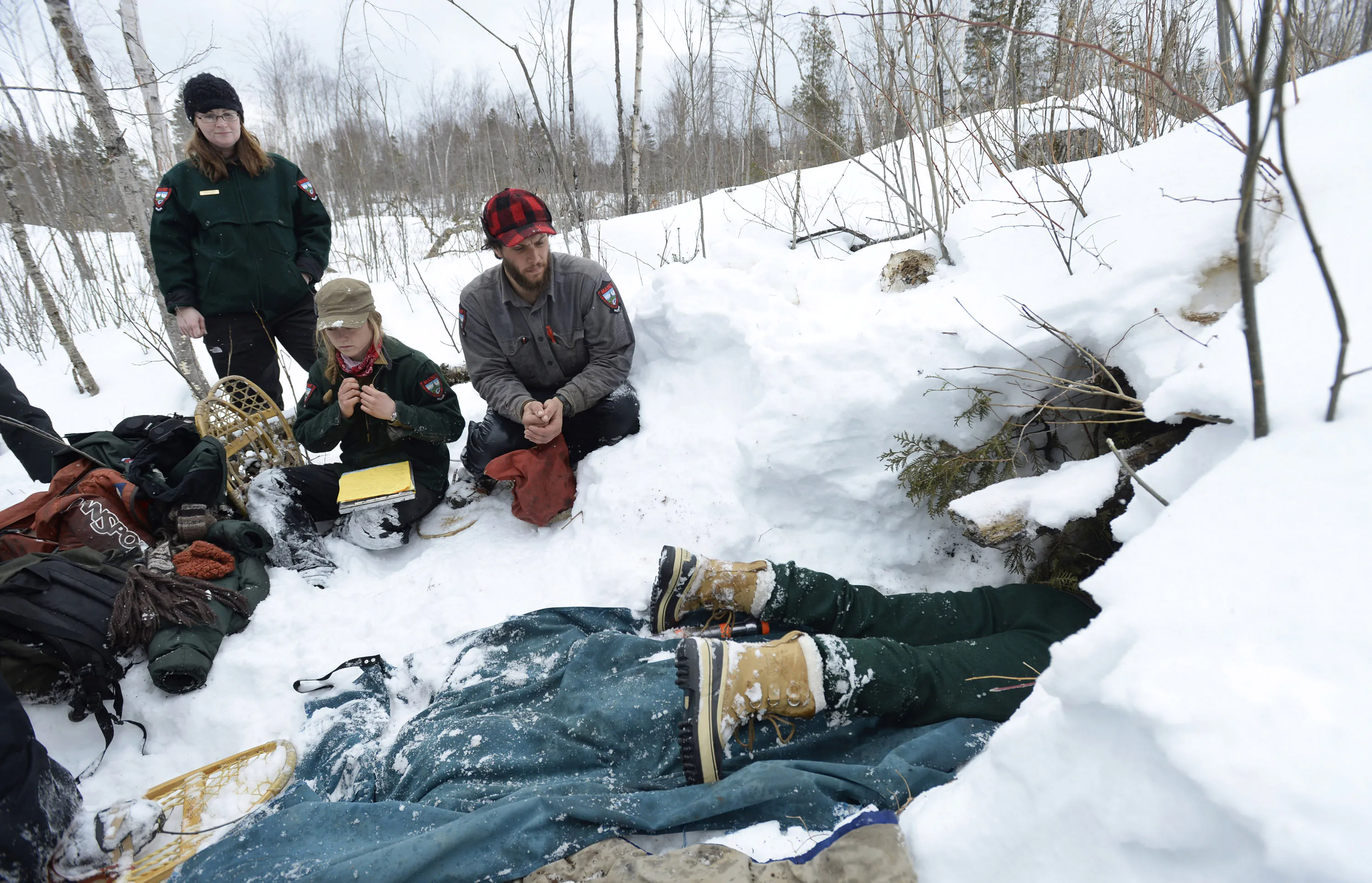 Une photo de biologistes entourant une tanière d'ours neigeuse dans le Maine.
