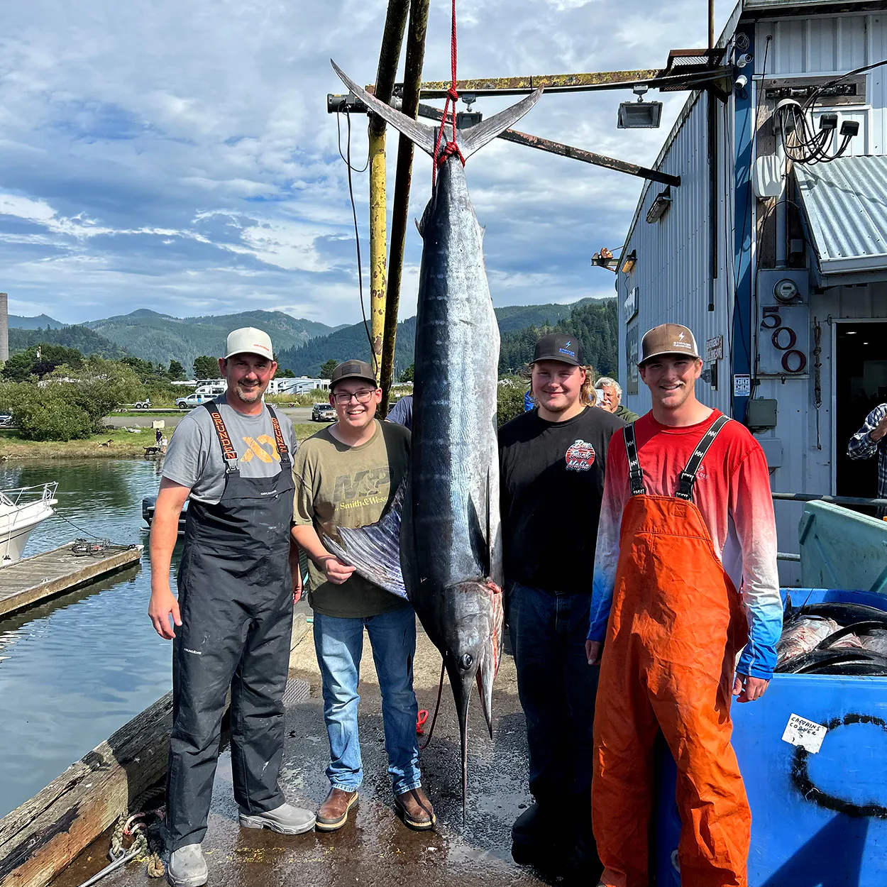 Une équipe de pêcheurs offshore avec un gros marlin rayé sur l'échelle.