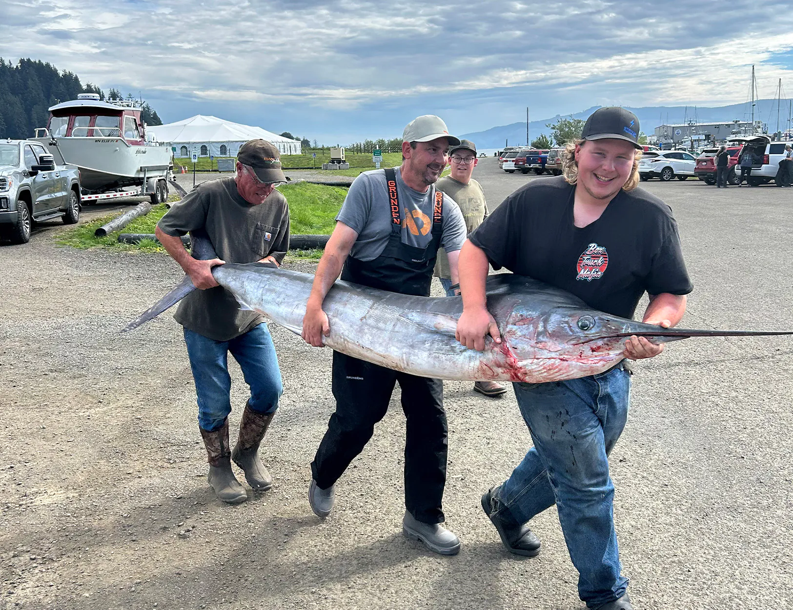 Quelques pêcheurs portent un marlin rayé à une échelle.