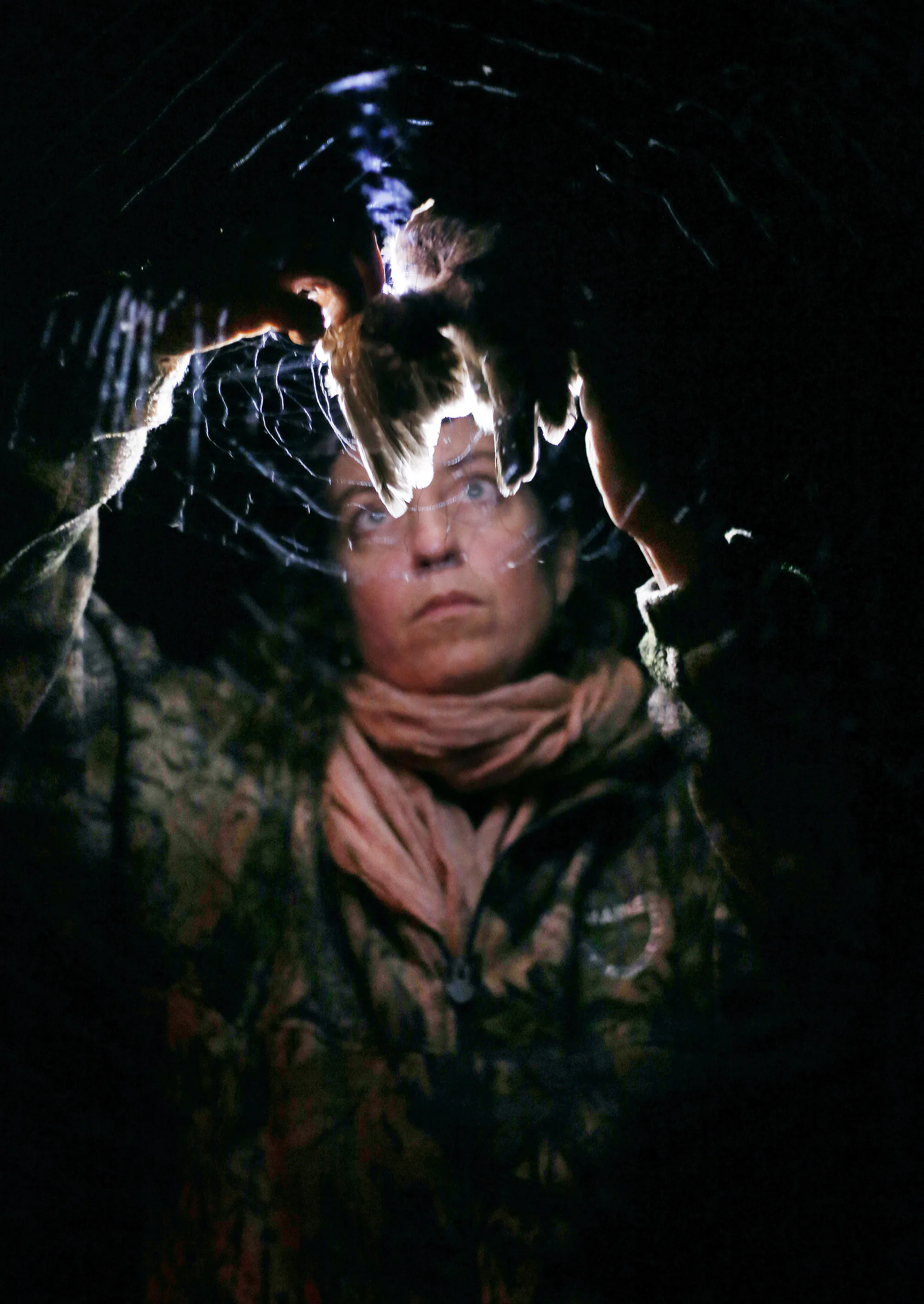 Une photo nocturne d'une femme libérant un oiseau de ce qui ressemble à un filet ou à une araignée.