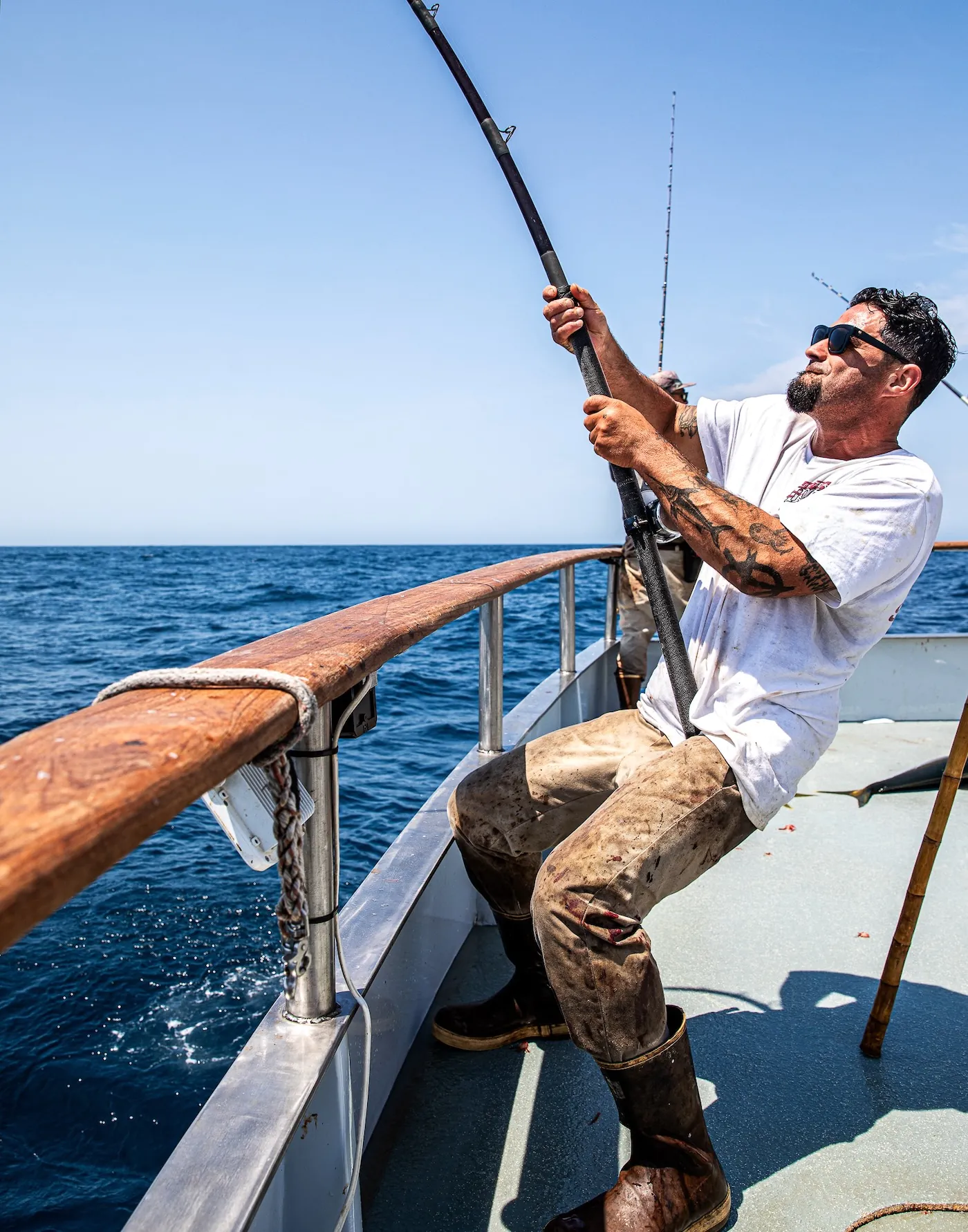 Un homme combat un poisson au large.