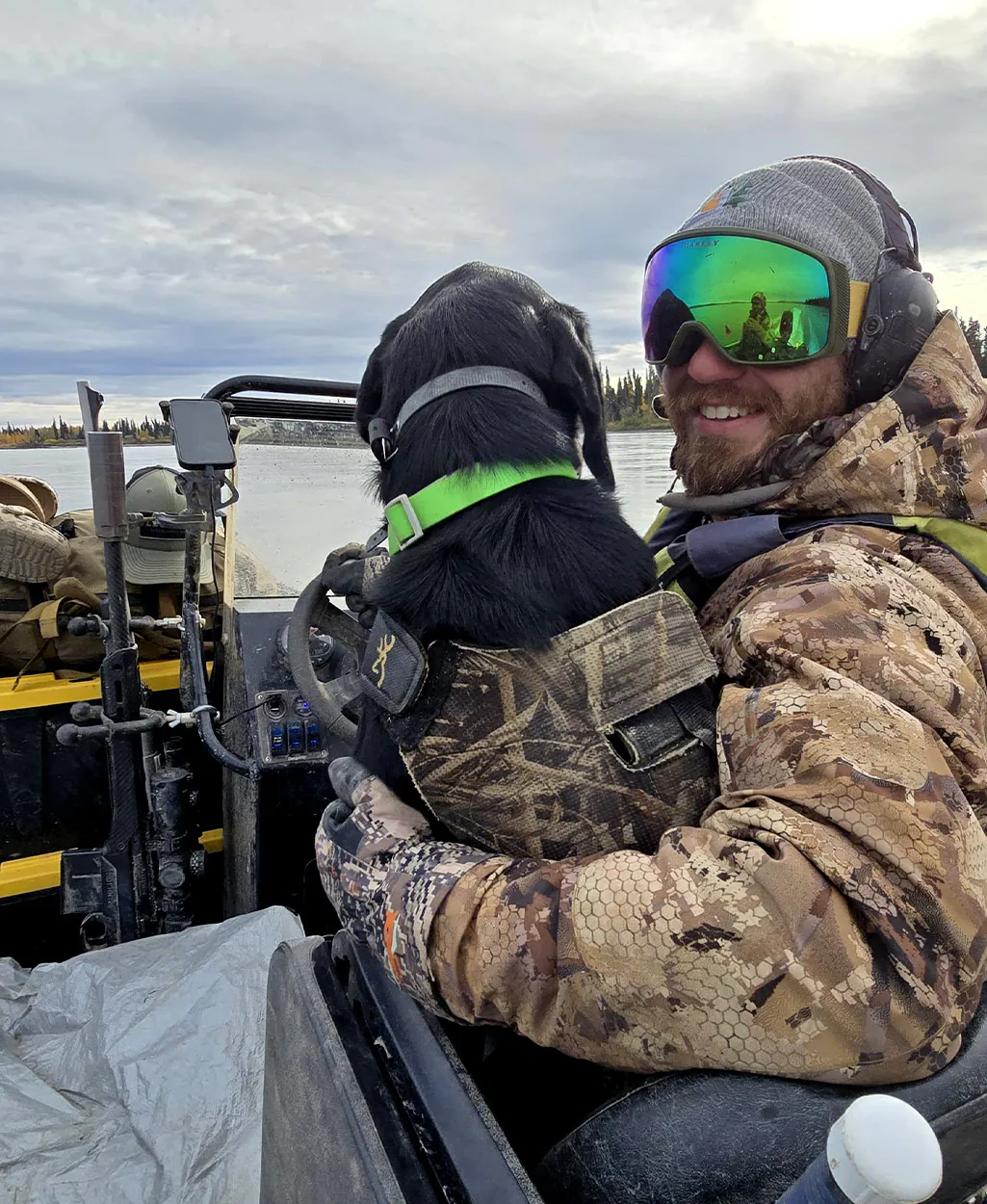 Un chasseur et son chien courent en amont dans un bateau.
