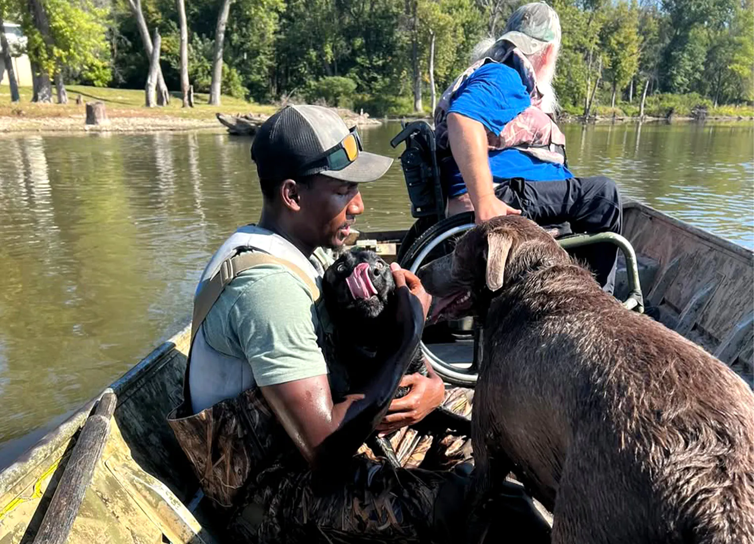 Un chasseur embrasse son laboratoire noir dans un bateau.