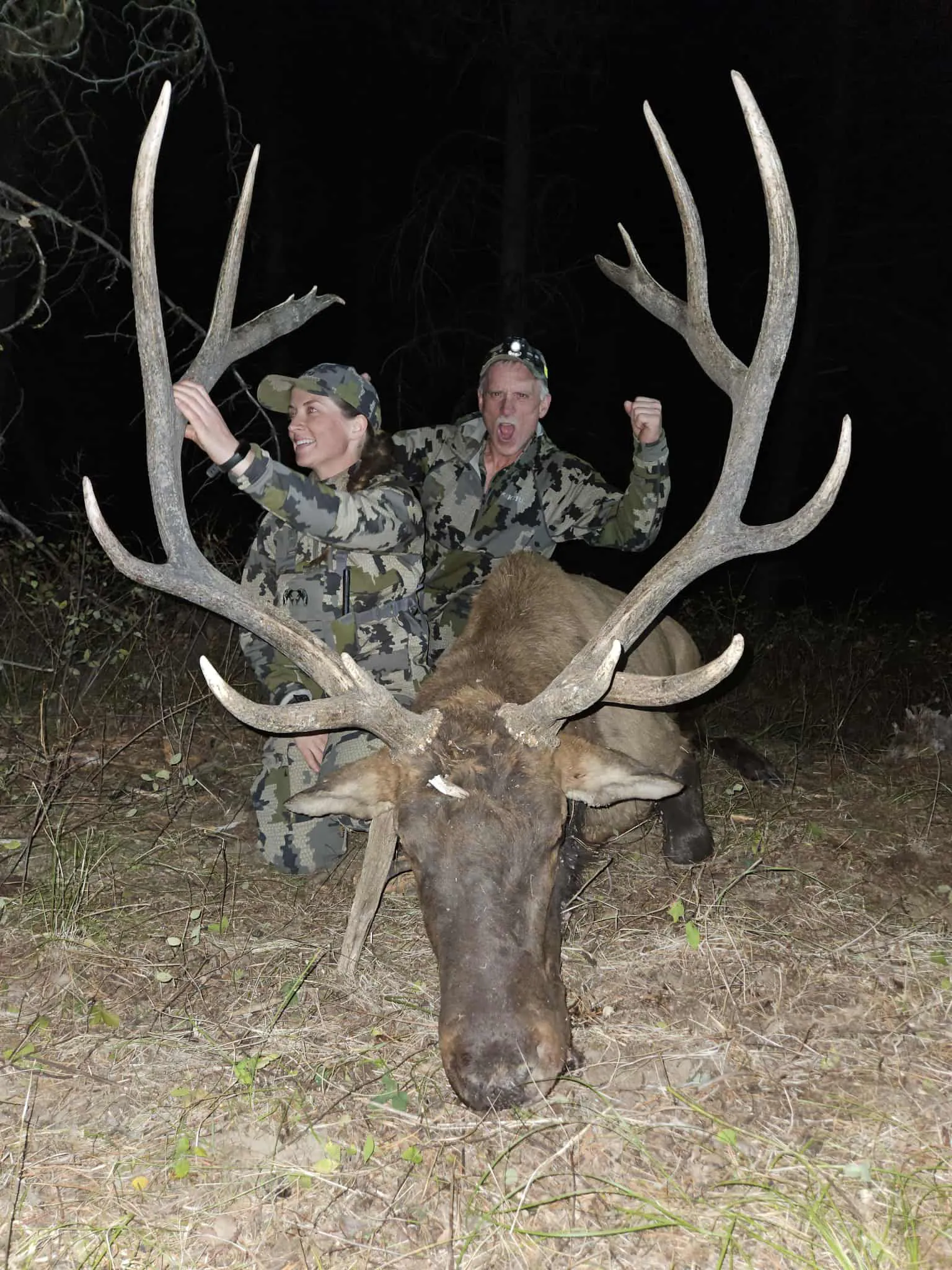 Deux chasseurs derrière un wapiti mâle.