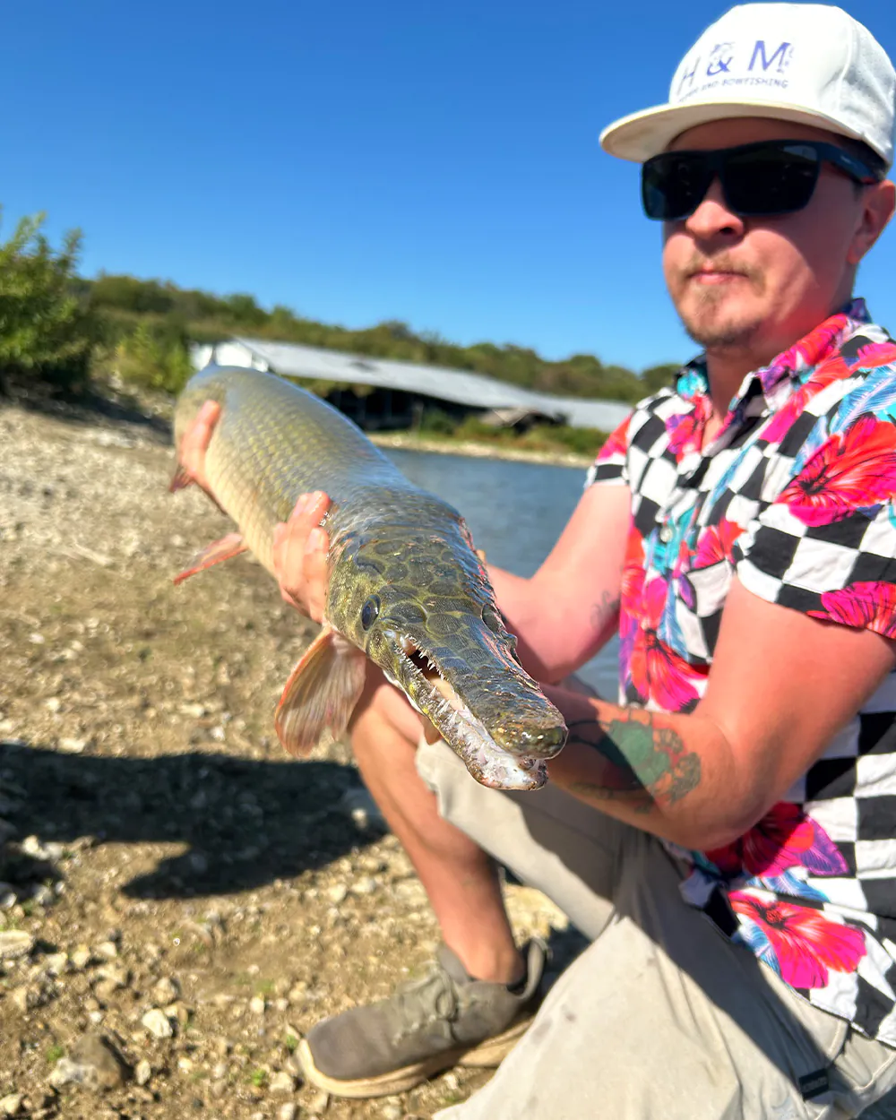 Un pêcheur tient un lépisosté tacheté pour un gros plan.
