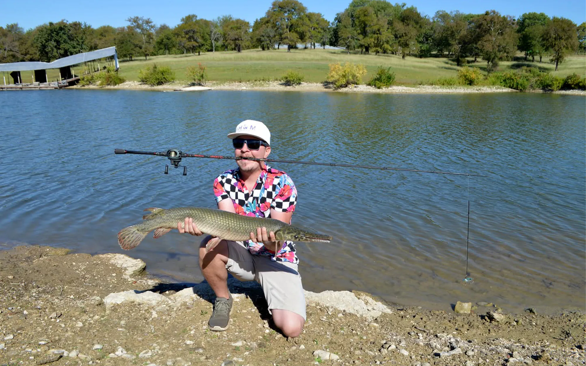 Un pêcheur brandit un gros gar et une canne cassée.