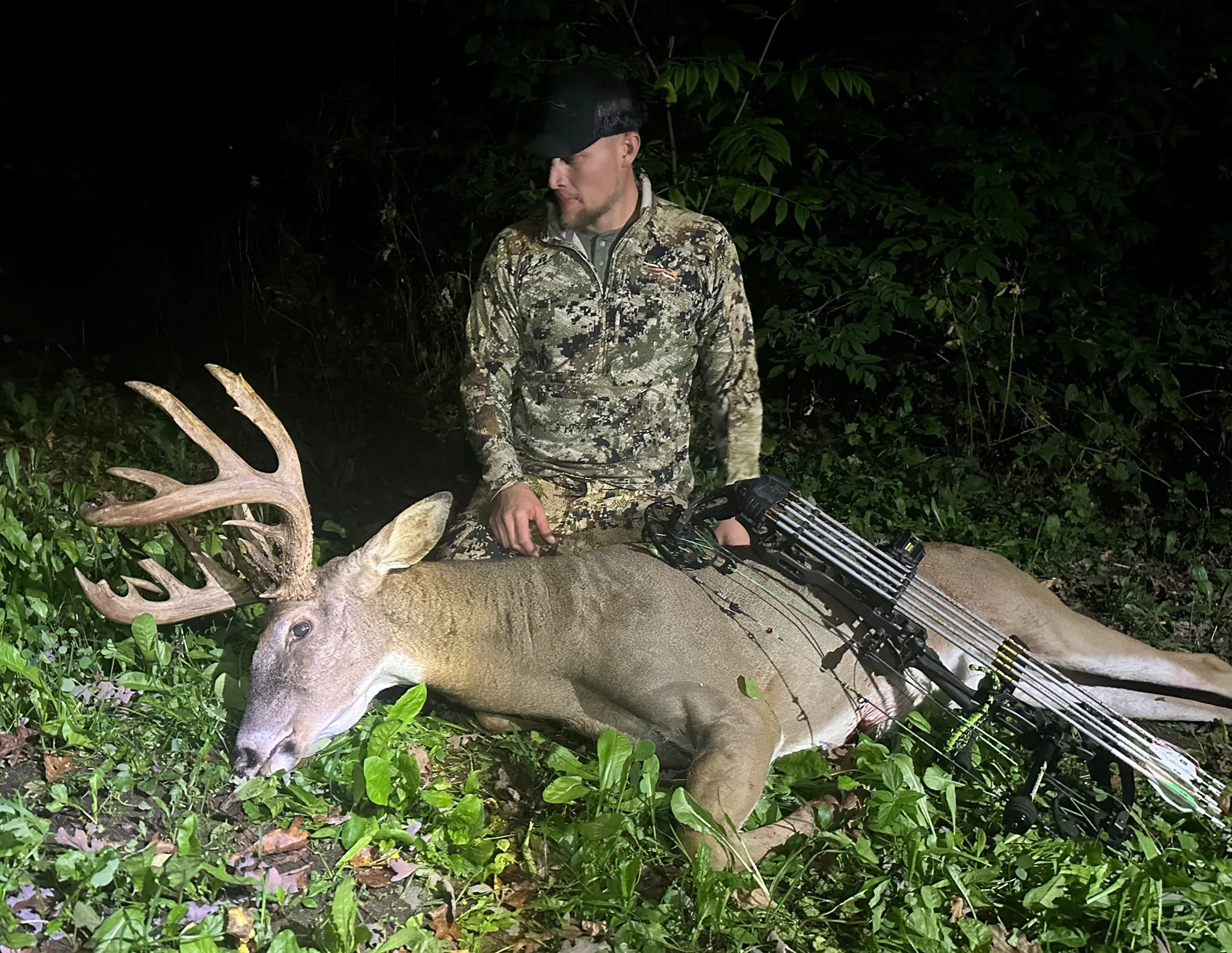 Un homme à Sitka Camo regarde un gros mâle qu'il était fléchi.