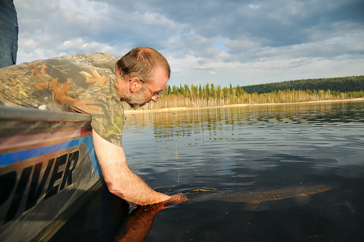 l'homme en bateau tient le poisson par la queue sous l'eau