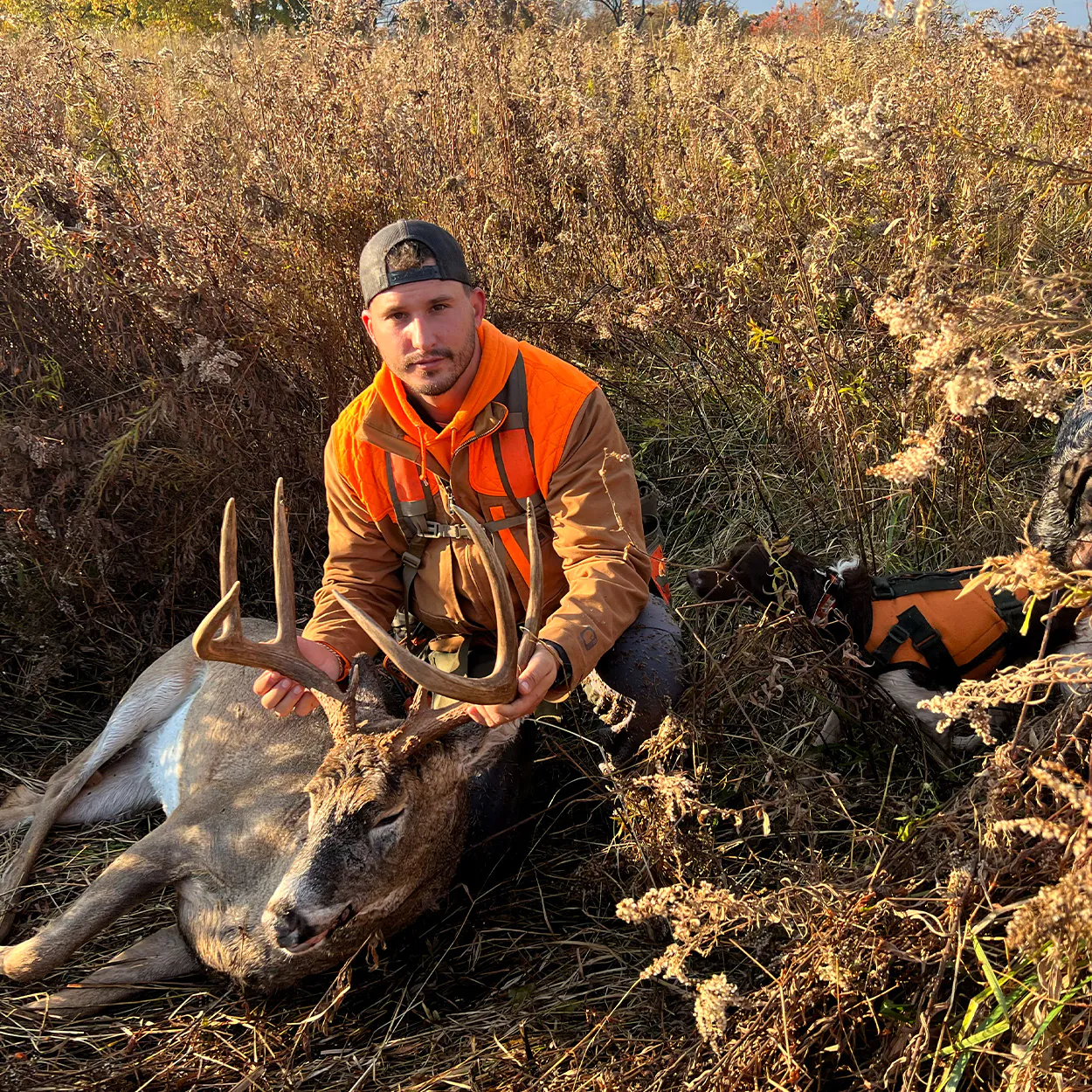 Un chasseur de faisan brandit un cerf qu'il a trouvé.