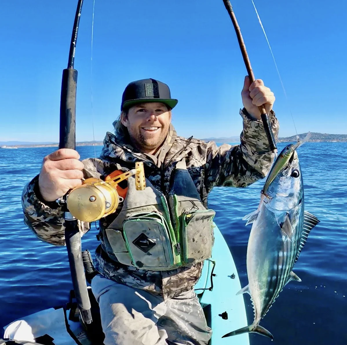 Un pêcheur en kayak hauturier tient un poisson pour la caméra.
