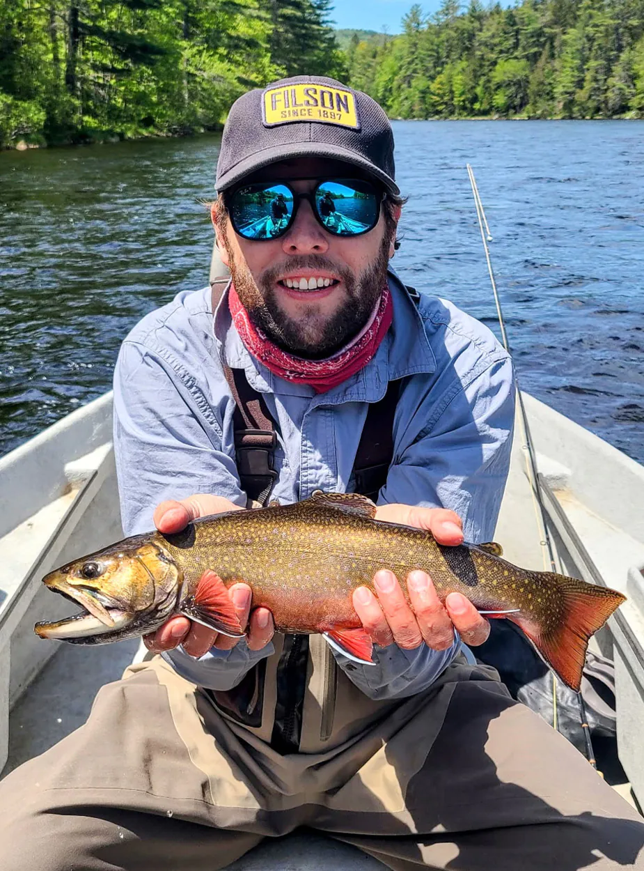 Un pêcheur à la mouche avec une truite mouchetée.