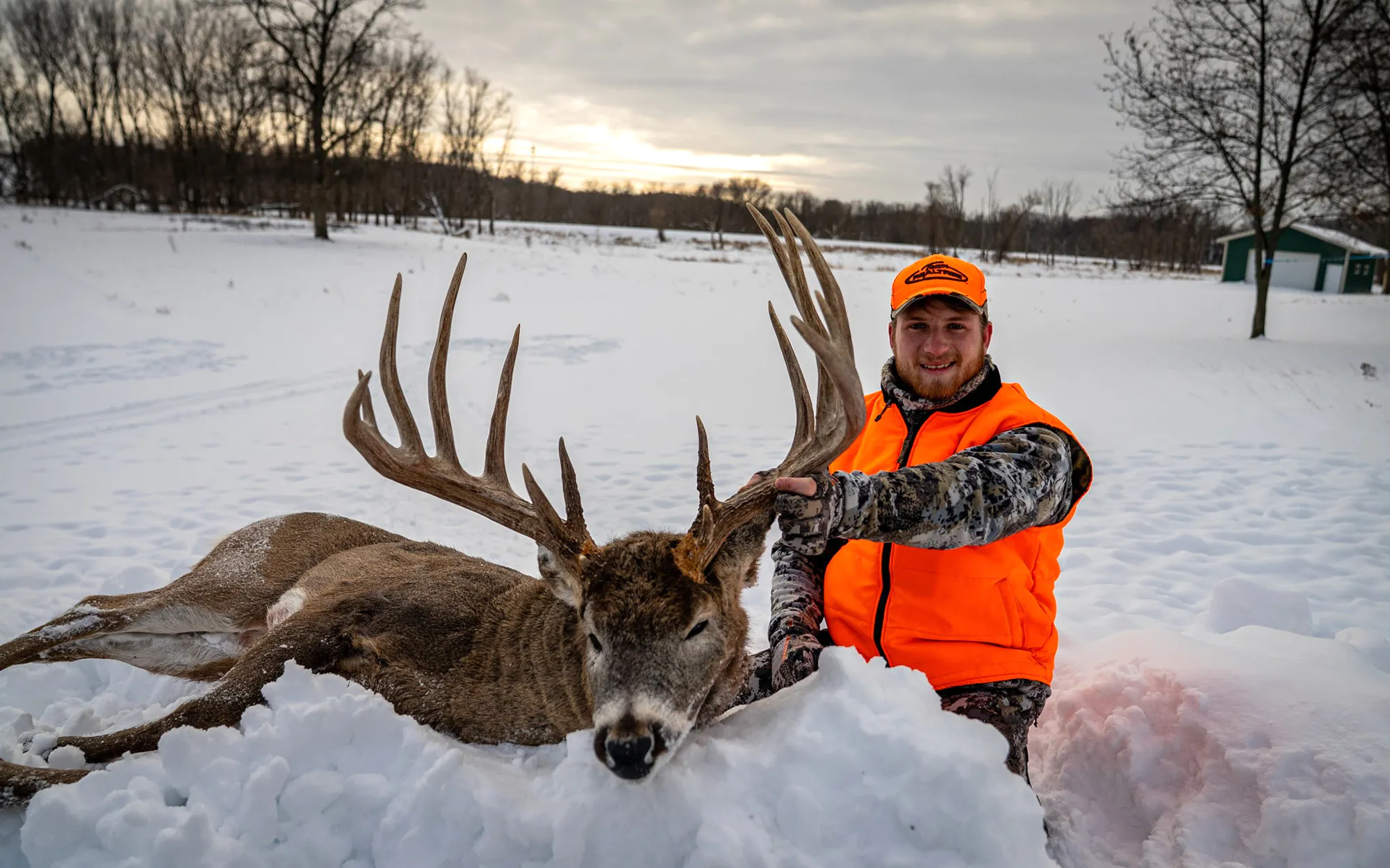 Un chasseur avec un gros mâle du Wisconsin dans la neige.