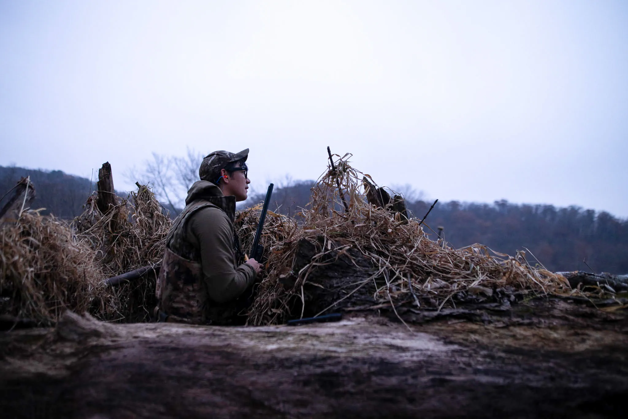 Un chasseur se cache derrière un tas de broussailles.