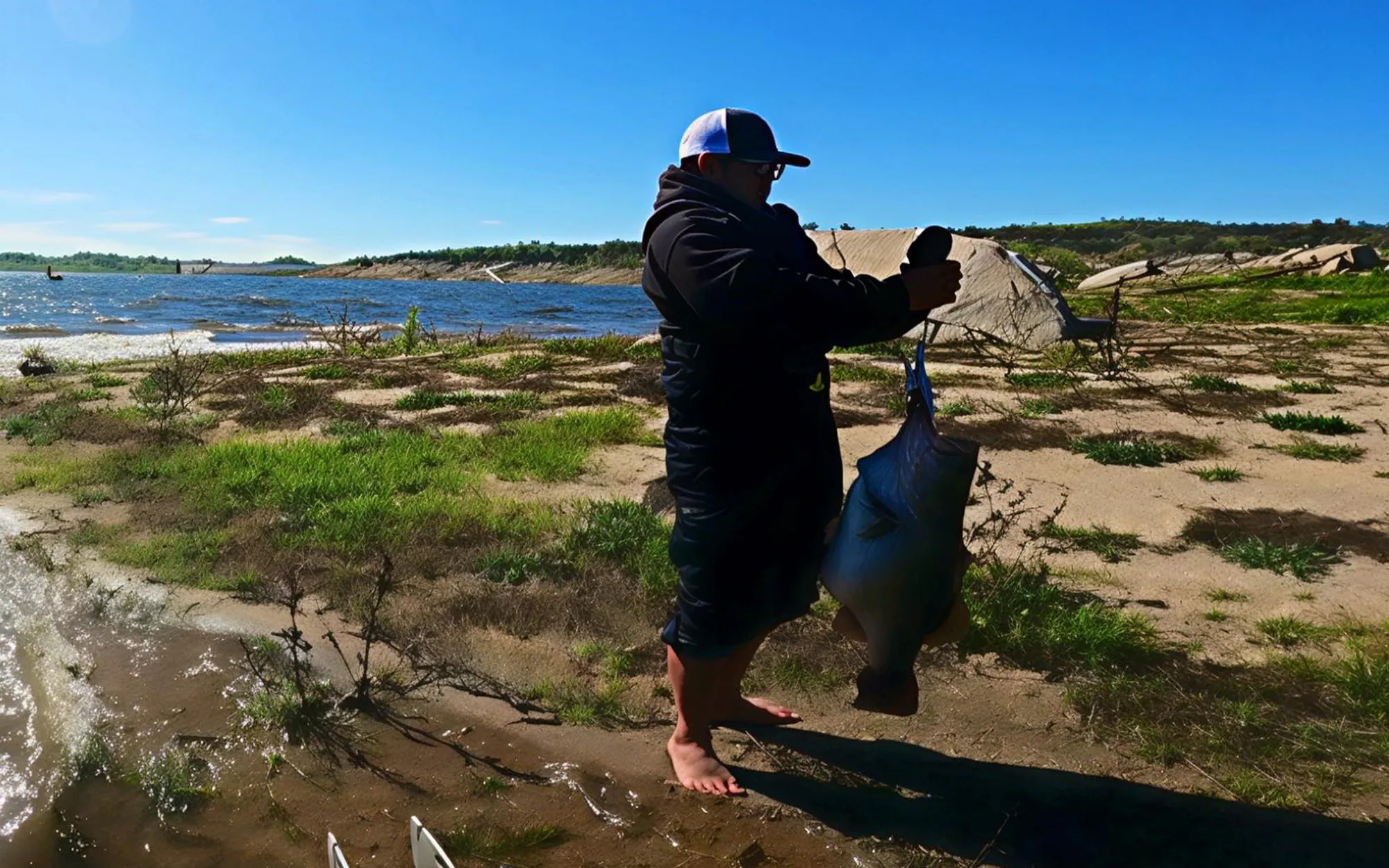 Un pêcheur pèse un énorme achigan à grande bouche sur terre.