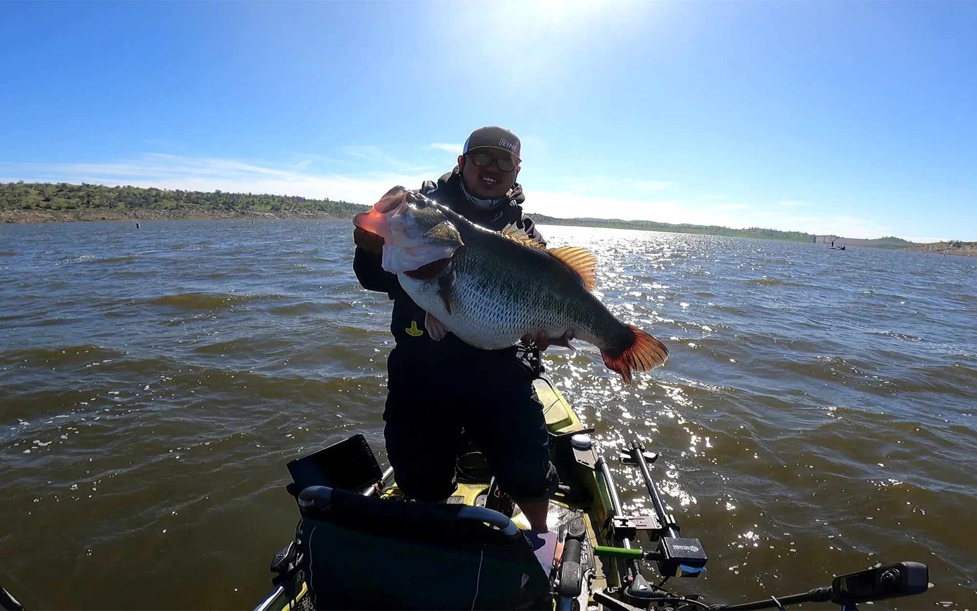 Un pêcheur de kayak californien avec un achigan géant à grande bouche.
