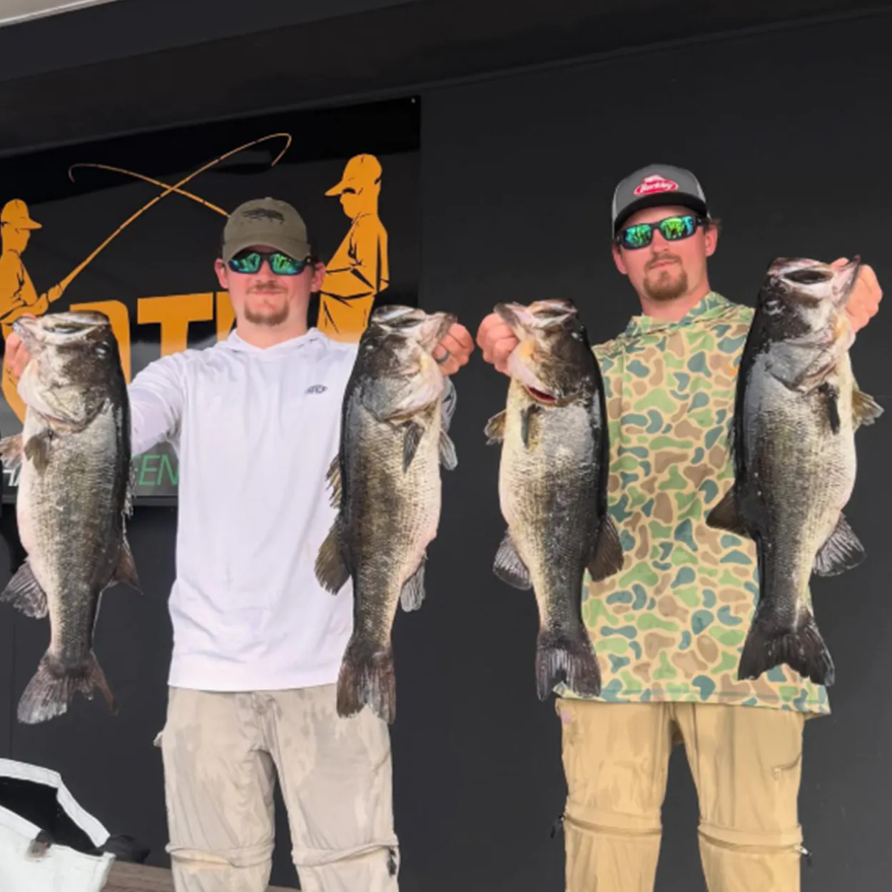 Deux pêcheurs brandissent une basse lors d'un tournoi.