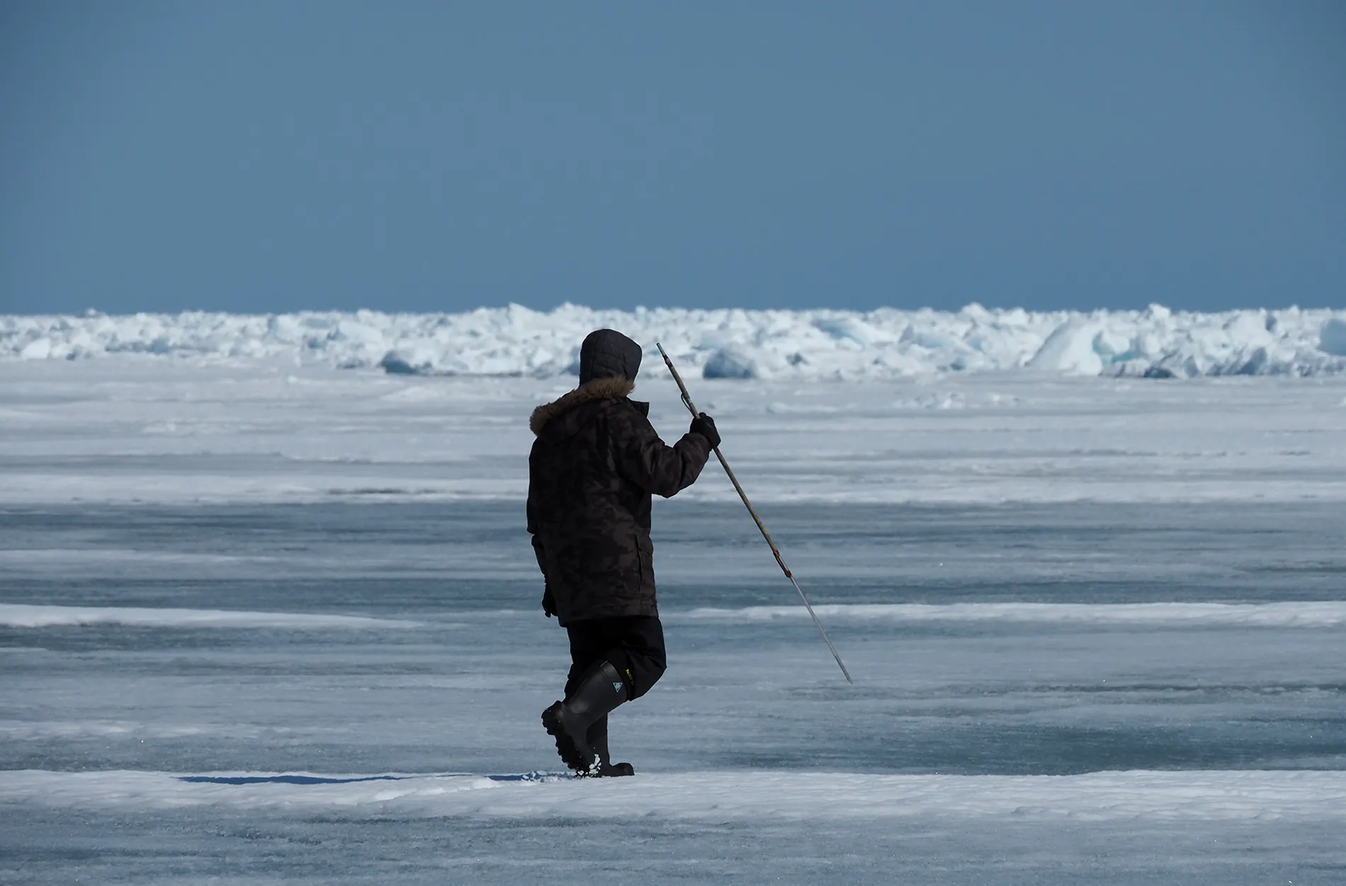 Un chasseur de phoques tient une lance sur la glace