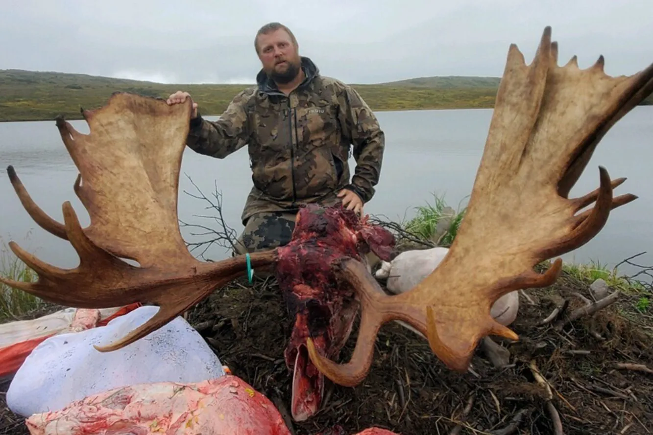 chasseur avec support d'orignal et viande au bord du lac