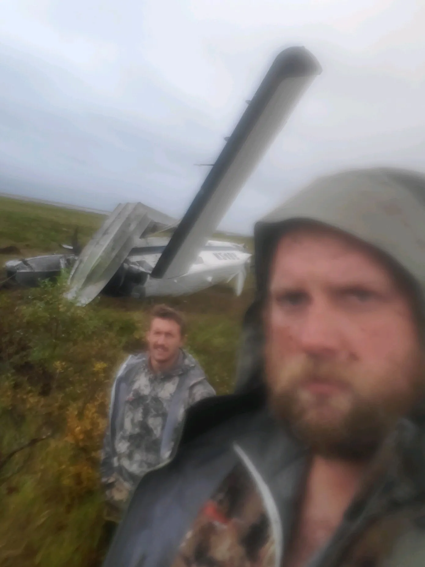 deux hommes avec une épave d'avion derrière eux