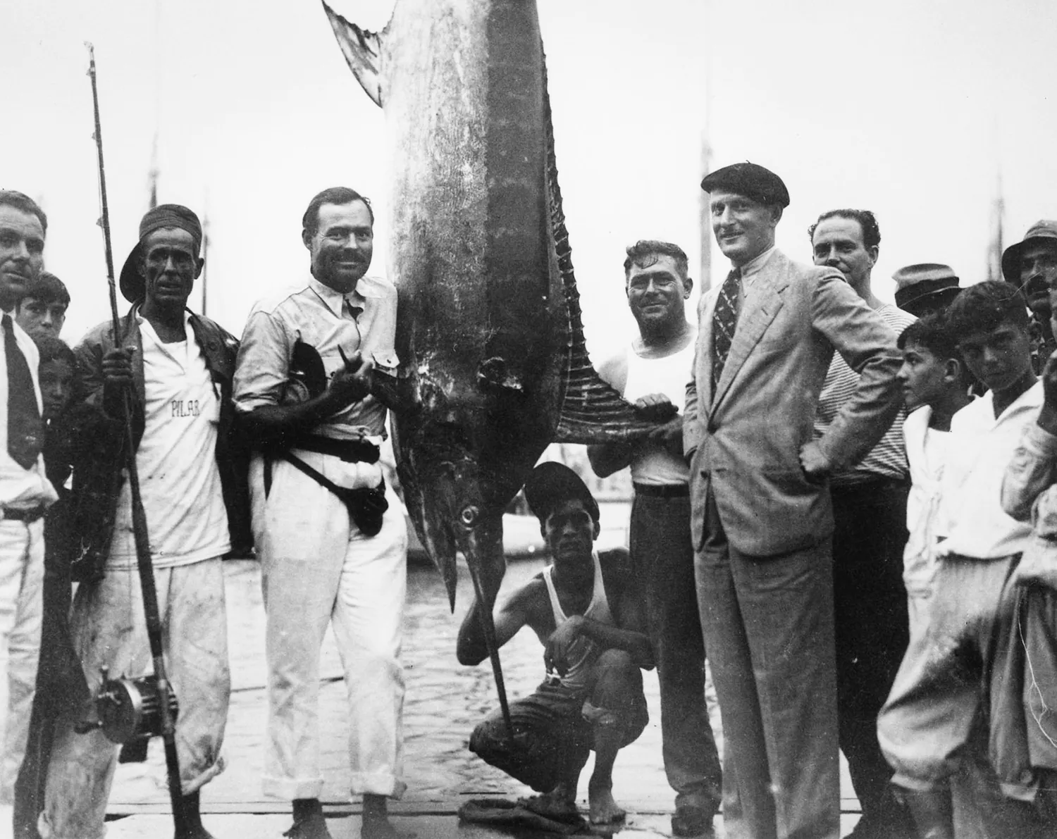 photographie historique d'Ernest Hemingway, d'un énorme marlin et d'une foule à la marina de Cuba.