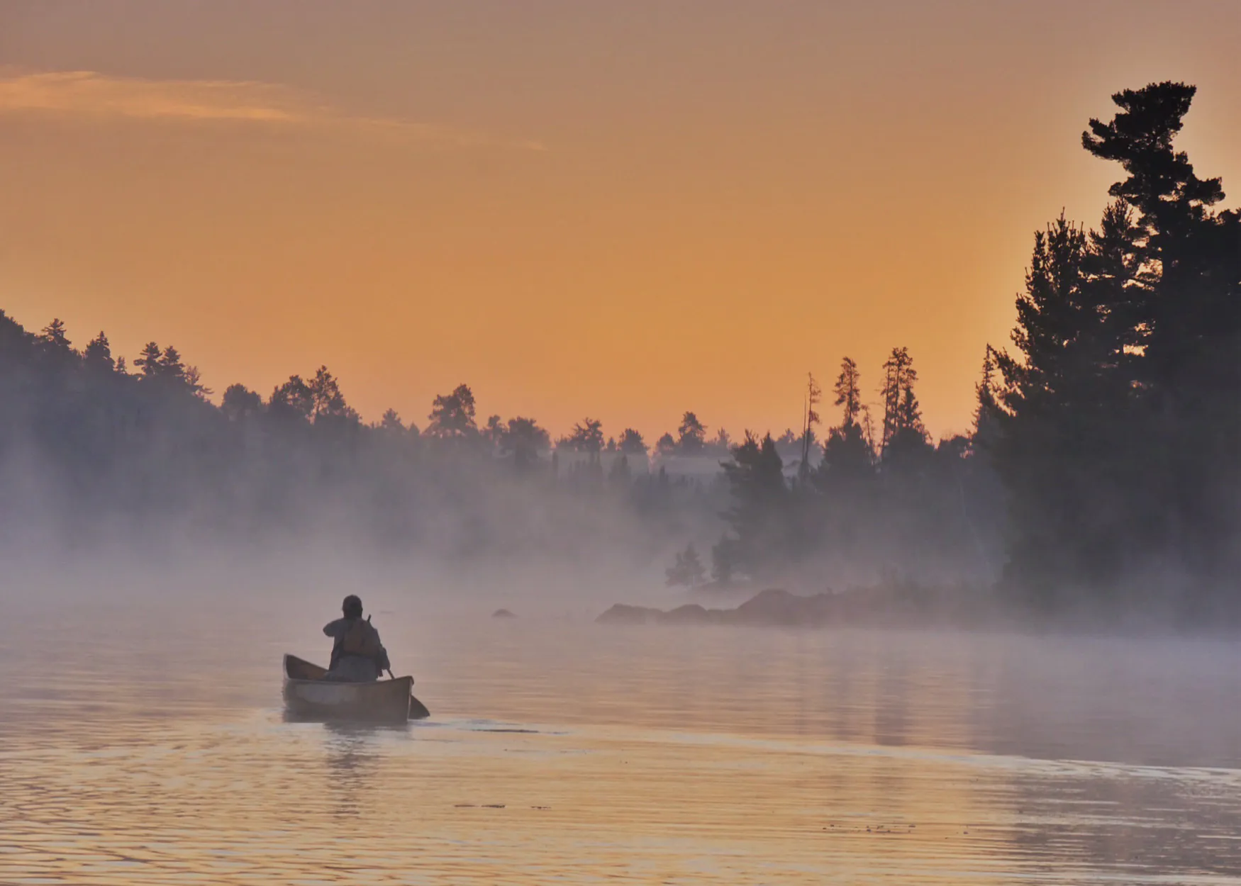 Un canoéiste solitaire sur un lac des eaux limitrophes.
