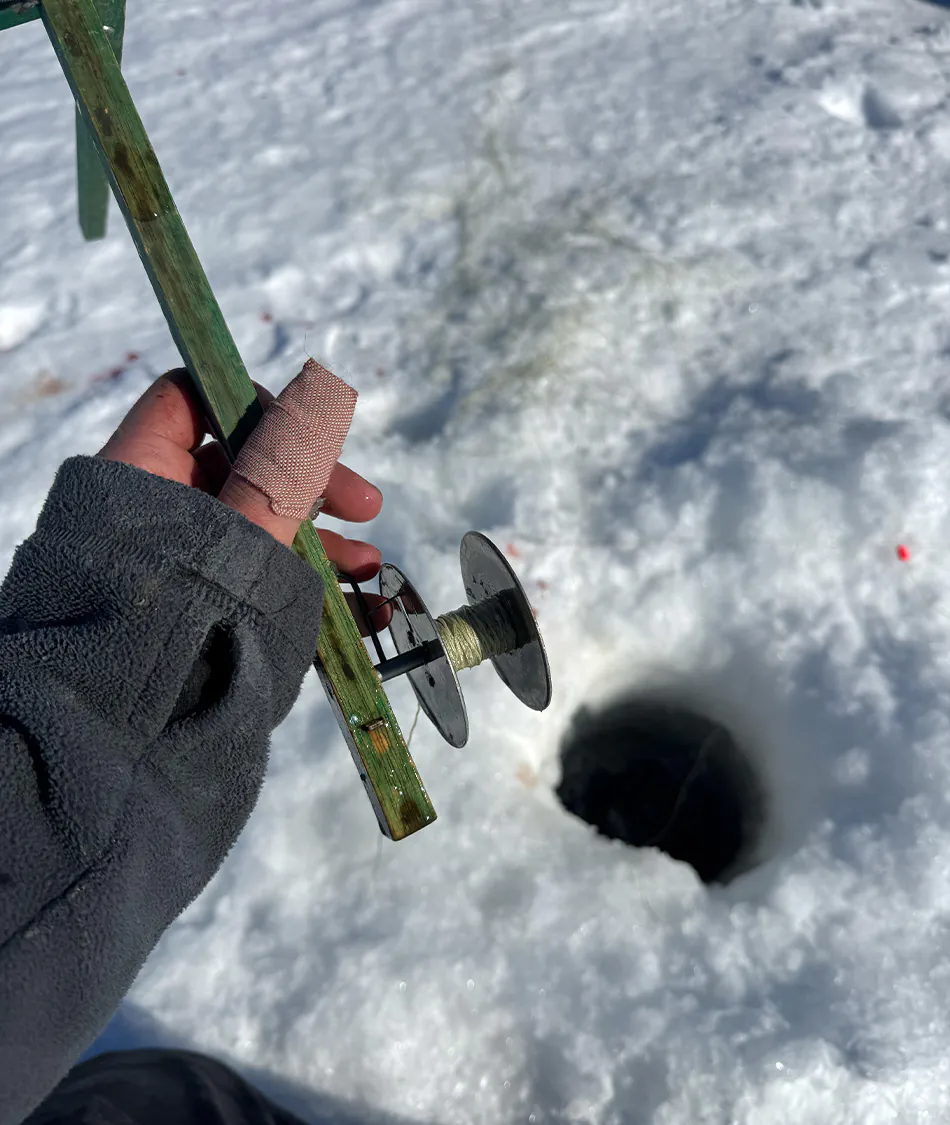 Un pêcheur regarde un trou dans la glace.