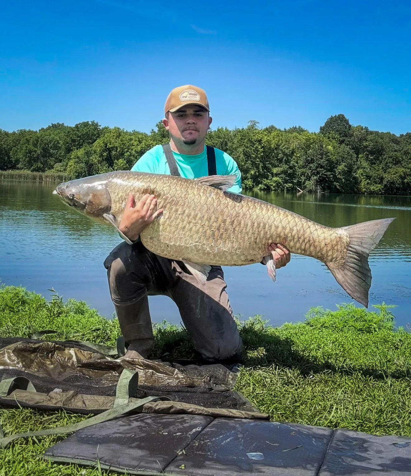 un pêcheur brandit une carpe record du monde.