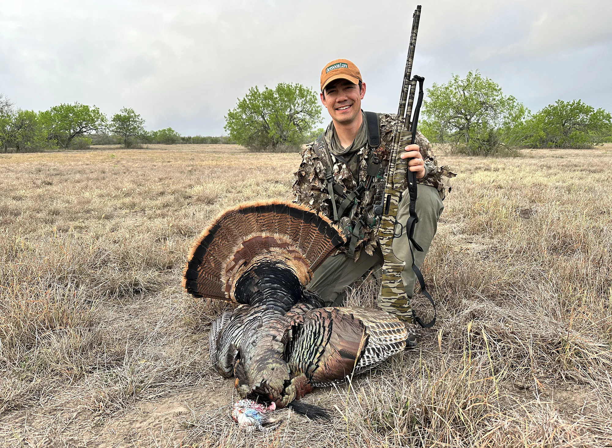 Un chasseur de dinde avec un chapeau orange et un oiseau mort